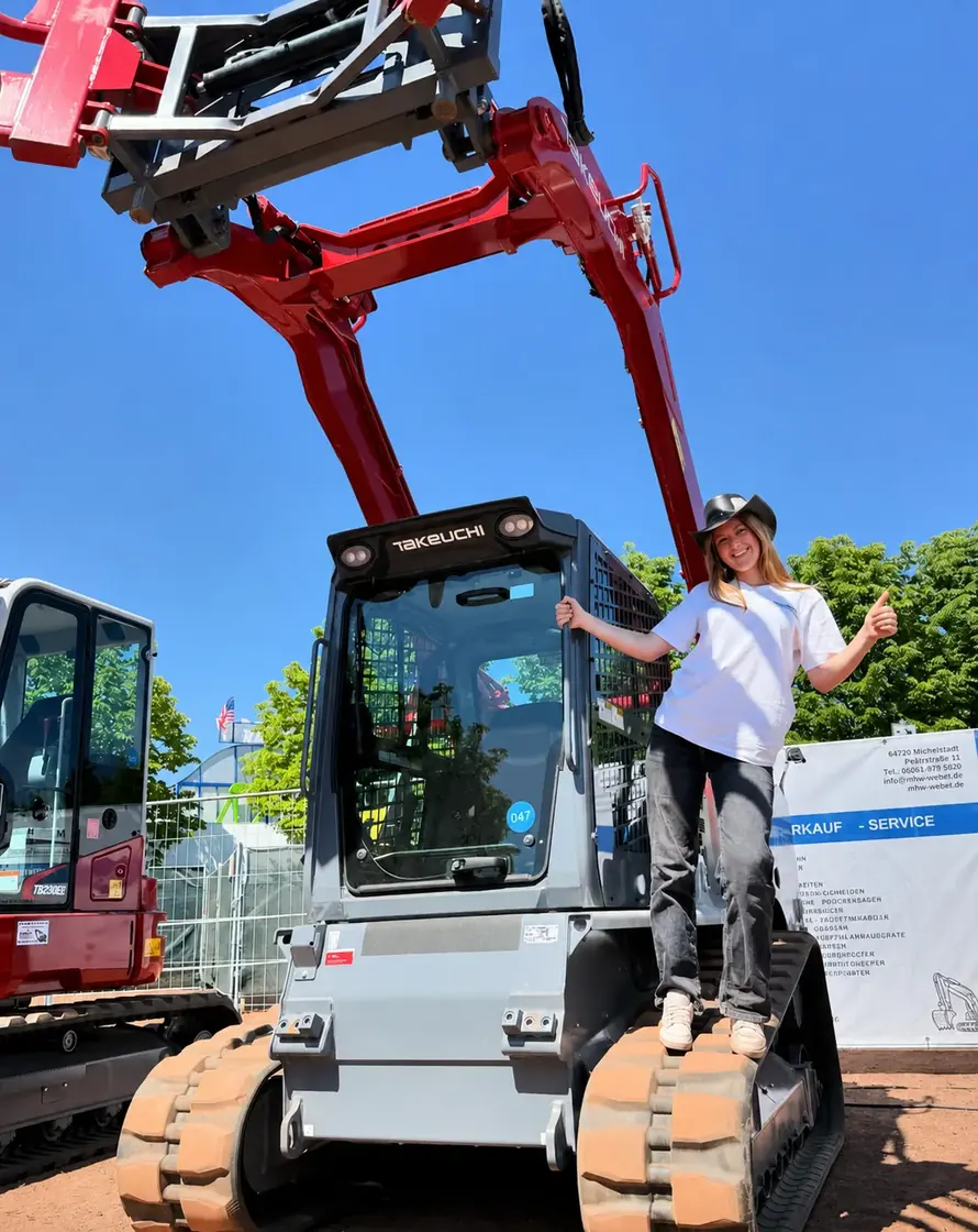 Eine Frau steht an einem Takeuchi-Bagger bei MHW
